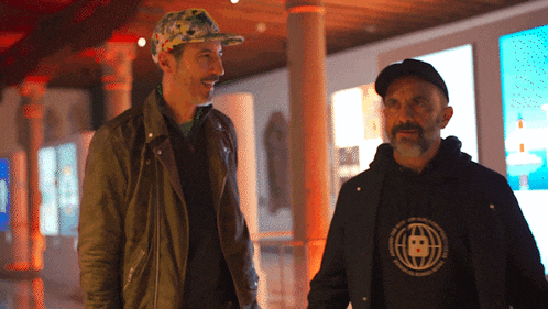 two men standing next to each other one wearing a hoodie with a circle on it that says ' a ' on it