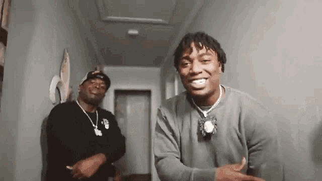 a couple of men are standing next to each other in a hallway .
