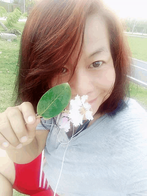 a woman holding a green leaf in front of her face with the number b612 on the bottom right
