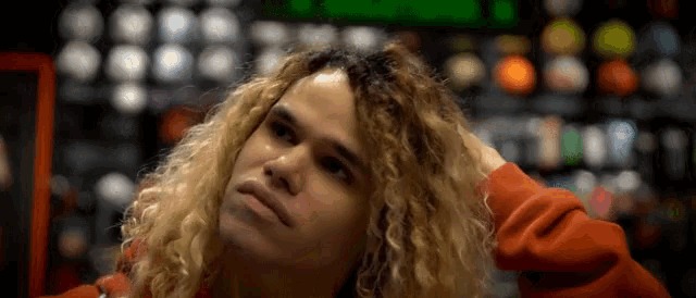 a young man with blonde curly hair is looking up