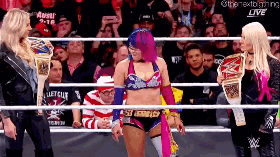 a female wrestler is standing in a ring talking to another wrestler .