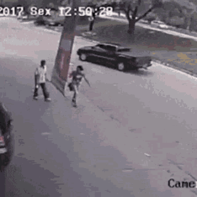 a man and a woman are walking down the street next to a car .