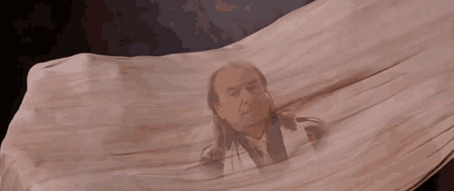 a man in a suit and tie is wrapped in a white cloth .
