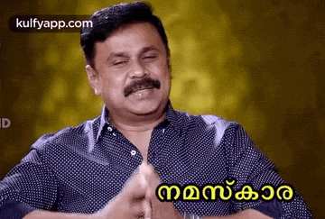 a man with a mustache is making a funny face with his hands folded .