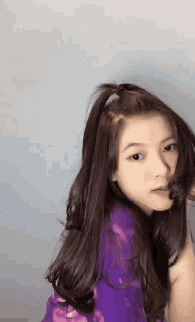 a young girl with long hair is wearing a purple shirt