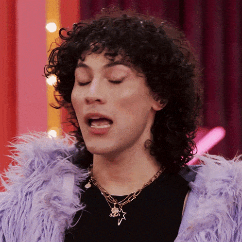 a man with curly hair is wearing a purple fur coat and necklace