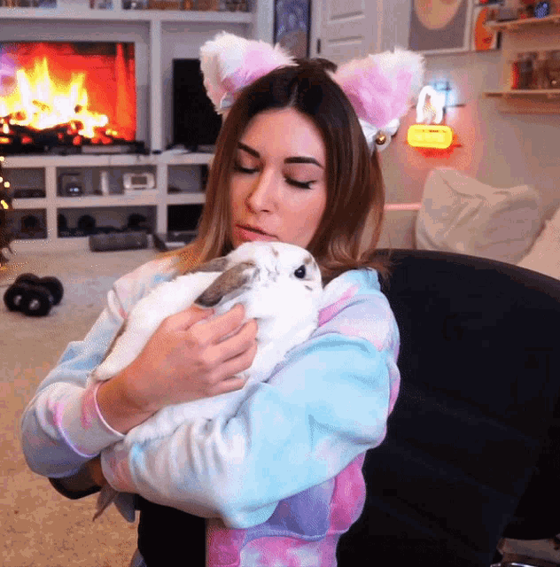 a woman wearing cat ears holds a white rabbit
