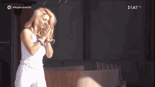 a woman in a white tank top is dancing in front of a sign that says #big brothergr