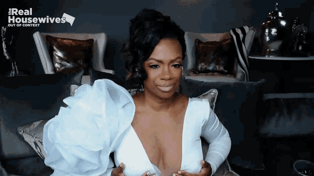 a woman in a white dress is sitting on a couch with the words real housewives out of context behind her