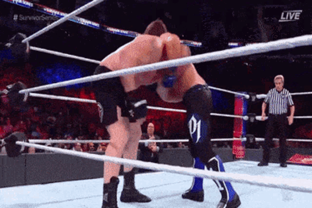 two men are wrestling in a ring with a referee and the words live on the bottom