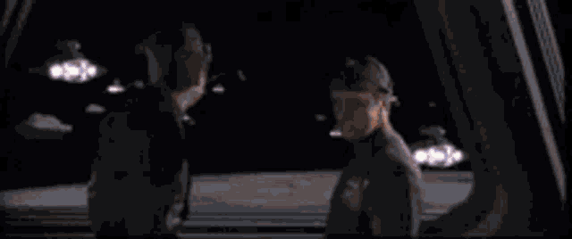 a couple of people are standing in a room with a lot of windows and lights .