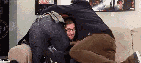 three men are hugging each other while sitting on a couch .