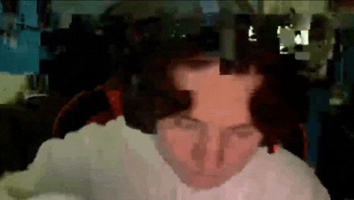 a man is sitting in a chair in front of a computer screen with a blurred image of his face .