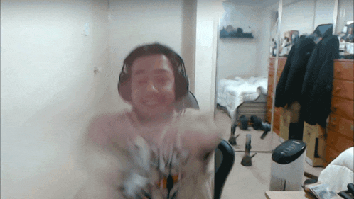 a man wearing headphones stands in a room with a trash can on the floor
