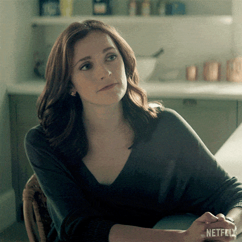 a woman is sitting at a table with a netflix logo on her wrist
