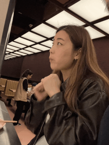 a woman sitting at a table with chopsticks in her hand