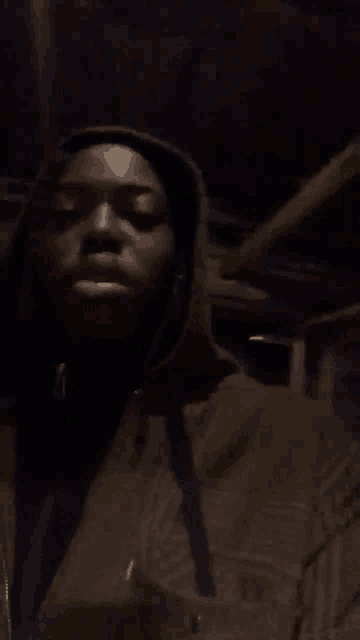 a man in a hooded jacket is standing in a dark room