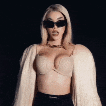 a blonde woman wearing sunglasses and a bra is standing in front of a black background .