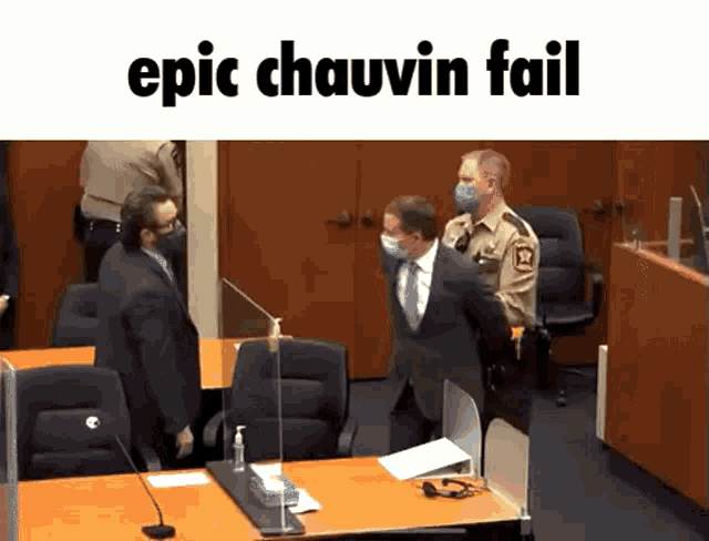 a man in a suit and tie is being arrested by a police officer in a court room .