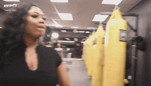 a woman stands in front of a row of yellow punching bags with the words nowthistv on the bottom right
