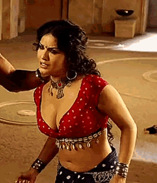 a woman in a red crop top and black pants is standing next to a man in a room .