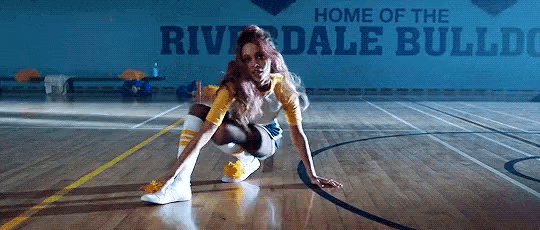 a woman is squatting on a basketball court in front of a sign that says riverdale bulldogs