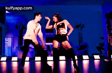 a man and a woman are dancing on a dance floor with the website kulfyapp.com in the corner .