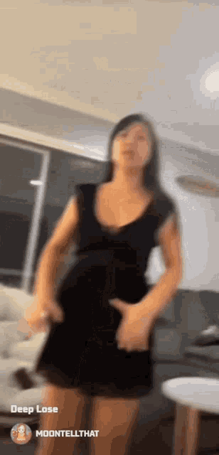 a woman in a black dress is dancing in a living room with a couch .