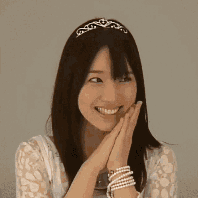 a woman wearing a white lace top and pearl bracelets smiles
