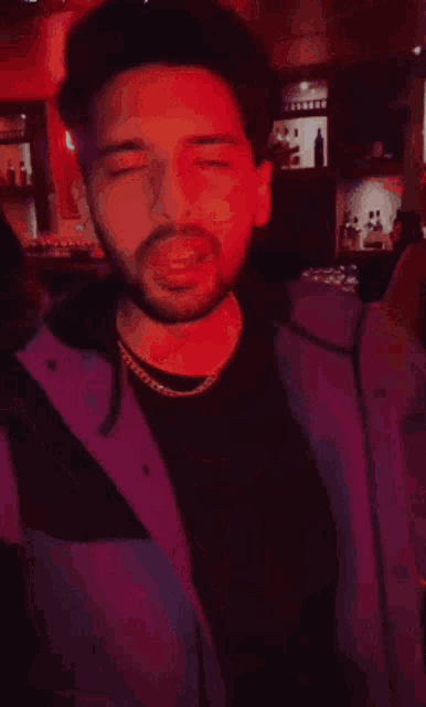 a man is making a face in front of a neon sign that says let 's di