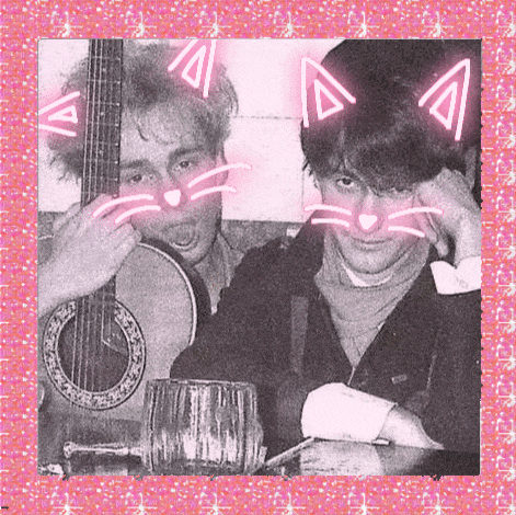 a man playing a guitar next to another man with cat ears on his face