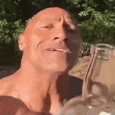 a man without a shirt is drinking from a bottle .
