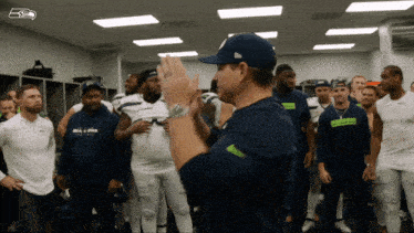 a man wearing a seahawks hat stands in a locker room