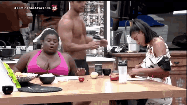 a woman in a pink bikini sits at a table with a man and a woman .