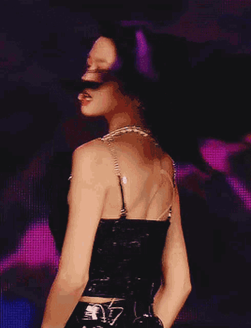 a woman in a black top and black pants is standing in front of a microphone .