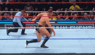 two men are wrestling in a wrestling ring with a referee