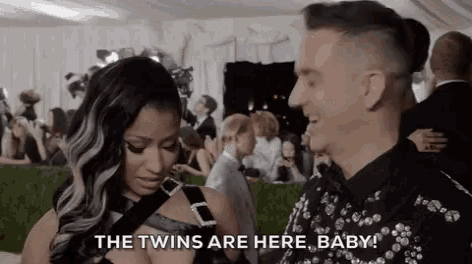 a man and a woman are standing next to each other and the woman is saying the twins are here baby
