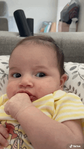a baby in a winnie the pooh shirt is sitting on a couch with his hand in his mouth