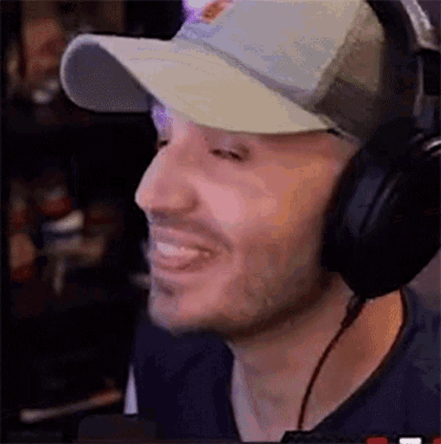 a man wearing a hat and headphones is smiling while playing a video game .