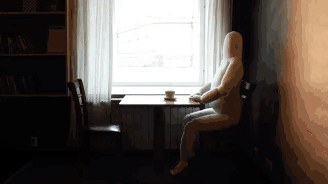 a mannequin sits at a table in front of a window