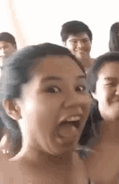 a woman is making a funny face while standing next to a group of people .