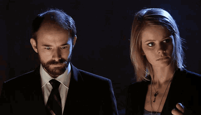a man in a suit and tie stands next to a woman with blonde hair