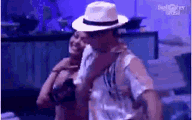 a man wearing a hat is holding a woman 's arm .