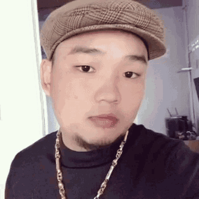 a man with a beard wearing a hat and a gold chain .