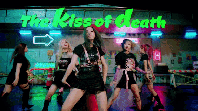 a group of young women are dancing in front of a neon sign that says the kiss of death