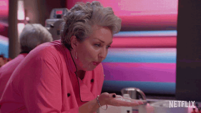 a woman in a pink shirt is standing in front of a netflix screen