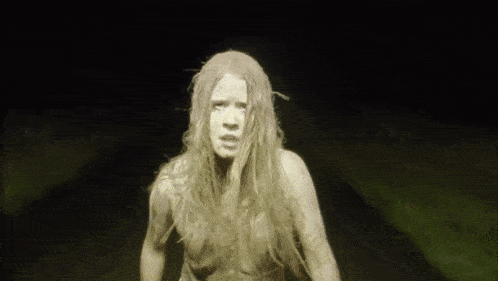 a woman with long blonde hair is standing in a dark room .