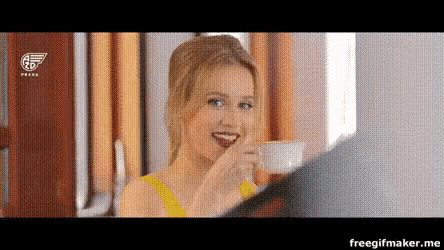 a woman in a yellow dress is drinking a cup of coffee