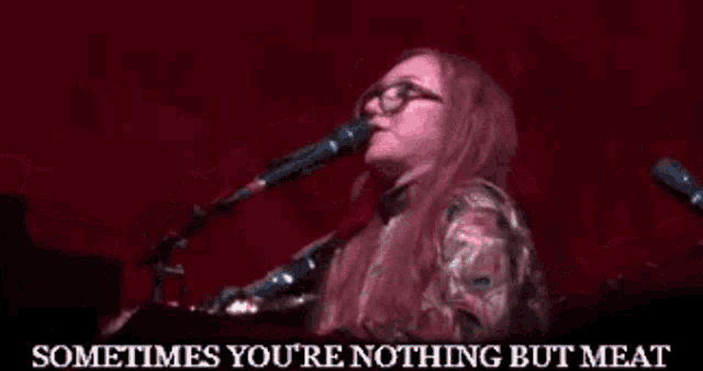 a woman singing into a microphone with the words sometimes you 're nothing but meat above her