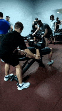 a man sitting on a bench with a dumbbell on his leg